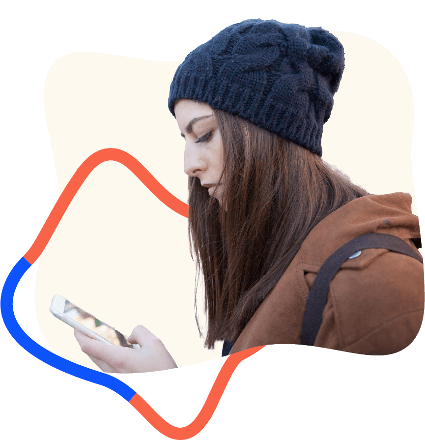 Teenage girl in a beanie looking at her smartphone with serious expression