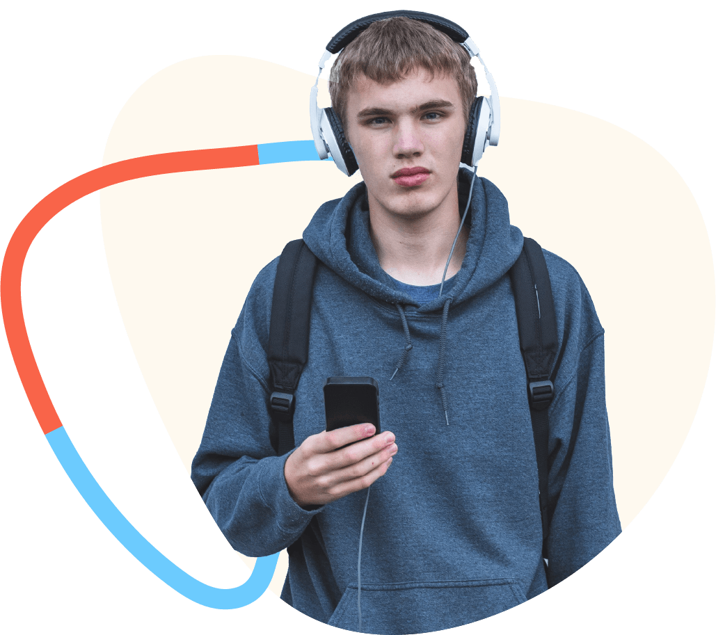 Teenage boy in sweatshirt wearing over the ear headphones with smartphone in hand