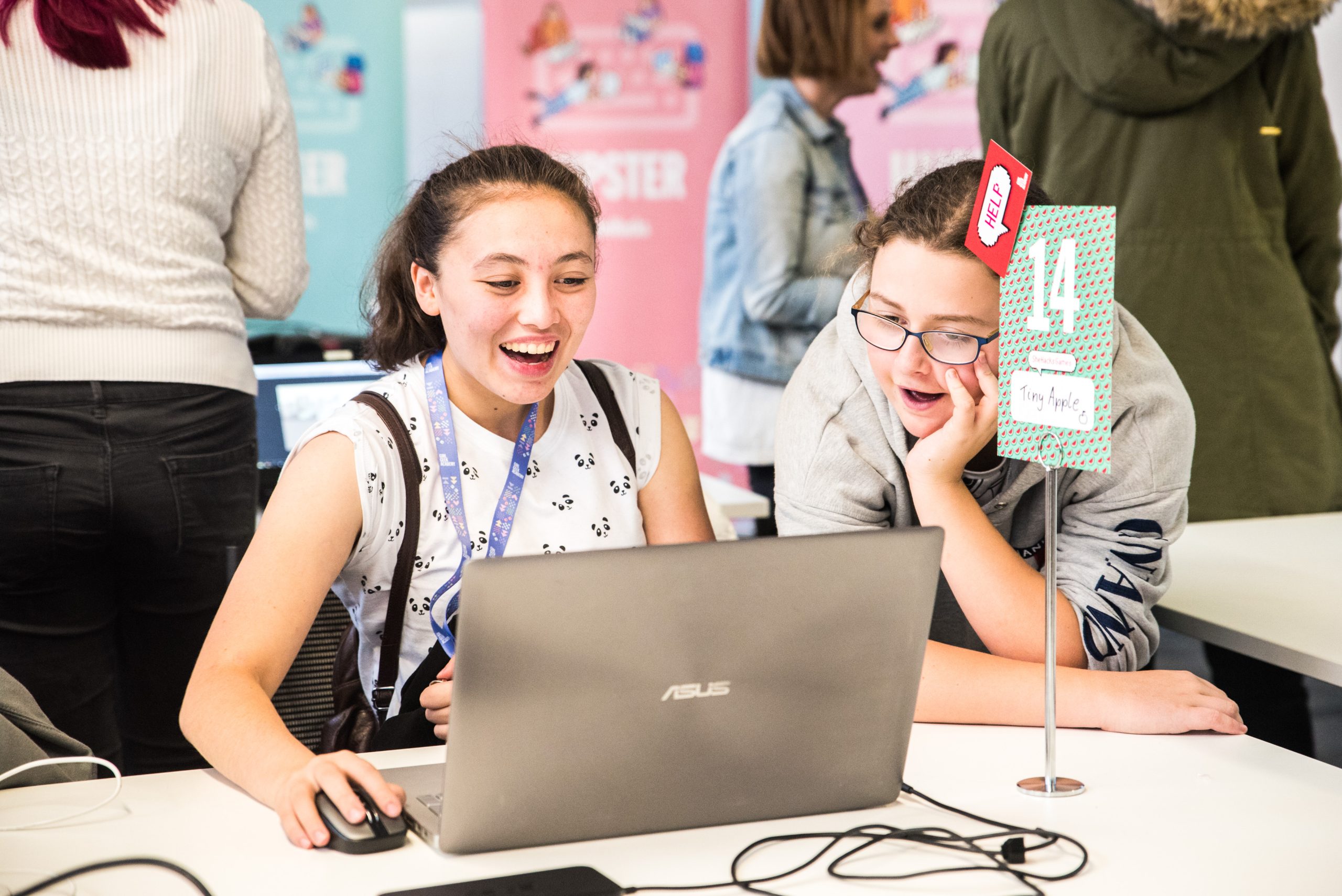 Two teenage girls smiling and working together on a laptop