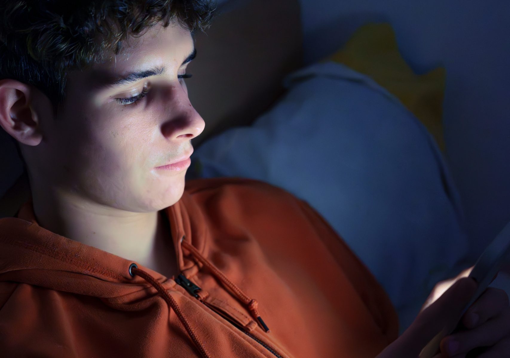 Teenager Lying in Bed at Night Using Smartphone